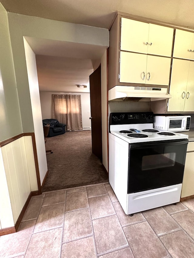 kitchen with a wainscoted wall, light colored carpet, electric range, white microwave, and under cabinet range hood