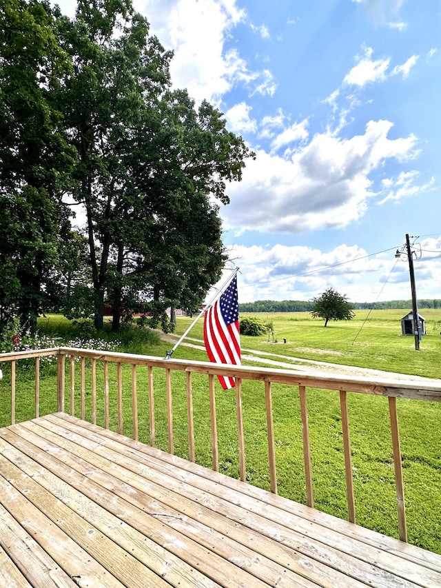 wooden deck with a rural view and a yard