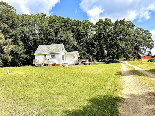 exterior space with dirt driveway, a deck, and a lawn