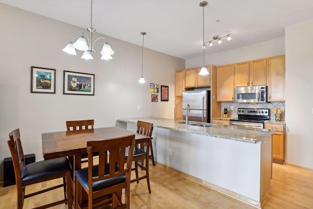 kitchen featuring stainless steel appliances, backsplash, light wood finished floors, and light brown cabinetry