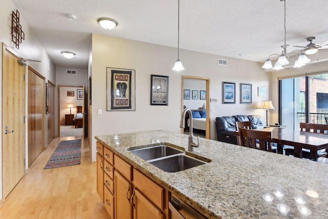 kitchen with decorative light fixtures, visible vents, a sink, and light wood-style flooring