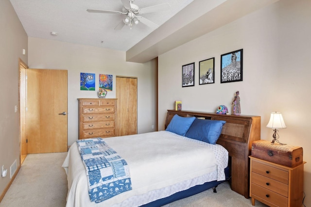 bedroom featuring light carpet, ceiling fan, and a closet