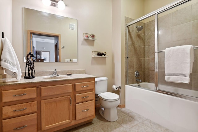 bathroom featuring toilet, bath / shower combo with glass door, tile patterned flooring, and vanity