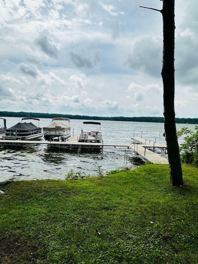 dock area with a water view and a yard