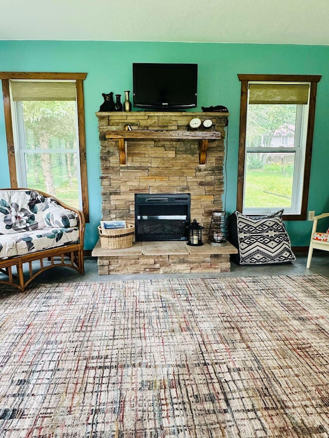 living room with a stone fireplace and a wealth of natural light