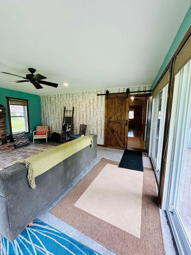 living room with a barn door and ceiling fan