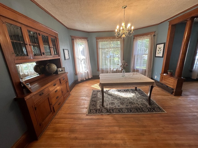 dining area with a chandelier, crown molding, light wood-style flooring, and a textured ceiling