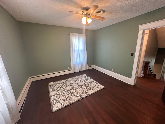 empty room featuring a textured ceiling, a ceiling fan, baseboards, baseboard heating, and dark wood finished floors