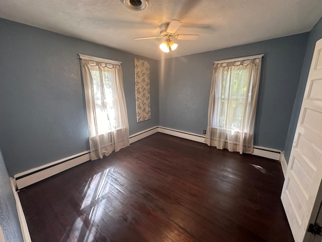 spare room with baseboards, ceiling fan, dark wood-type flooring, baseboard heating, and a textured ceiling