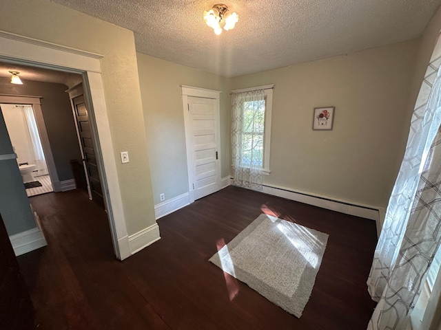 unfurnished bedroom featuring dark wood-style flooring, a closet, baseboard heating, a textured ceiling, and baseboards