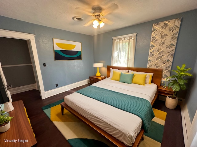 bedroom with a textured ceiling, a textured wall, a ceiling fan, baseboards, and dark wood finished floors