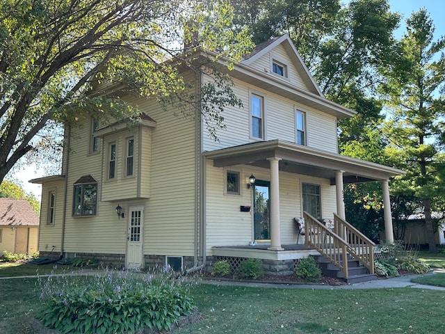 traditional style home featuring covered porch and a front lawn