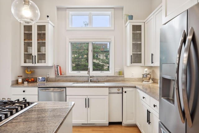 kitchen featuring white cabinets, light hardwood / wood-style flooring, appliances with stainless steel finishes, sink, and pendant lighting