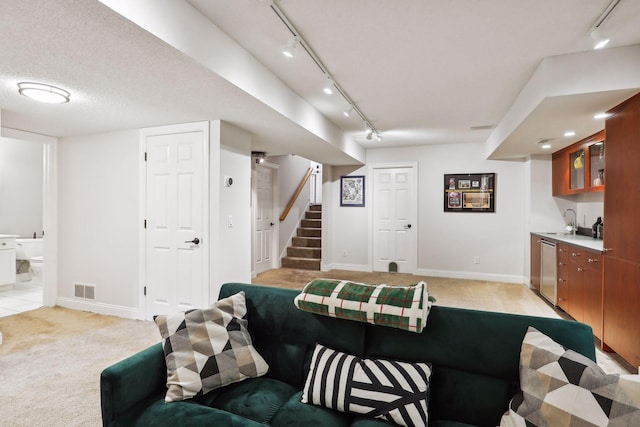 living room with indoor wet bar, a textured ceiling, rail lighting, and light colored carpet