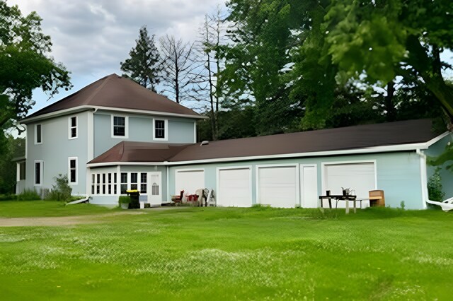 back of house featuring a lawn and a garage