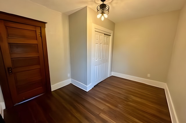 unfurnished bedroom with dark wood-type flooring and a closet