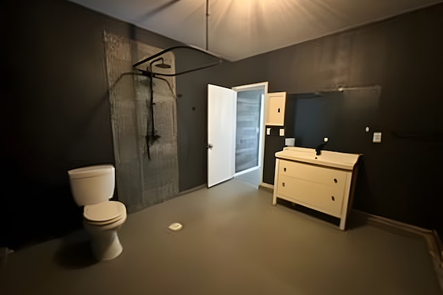 bathroom with a shower, vanity, concrete floors, and toilet