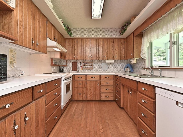 kitchen with white appliances, decorative backsplash, light hardwood / wood-style floors, and sink