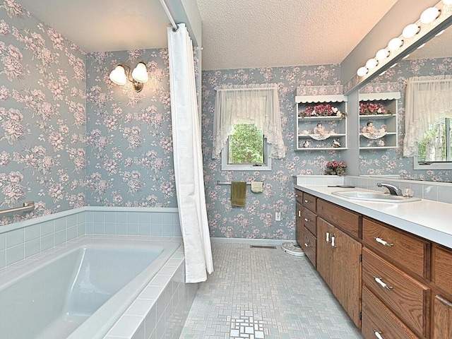 bathroom featuring tile patterned floors, tiled tub, a textured ceiling, and vanity