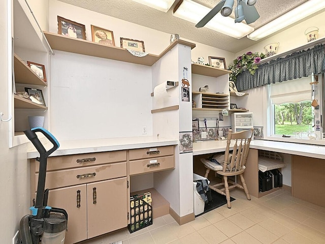 tiled office featuring built in desk, ceiling fan, and a textured ceiling