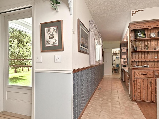 hallway featuring a textured ceiling and light tile patterned floors