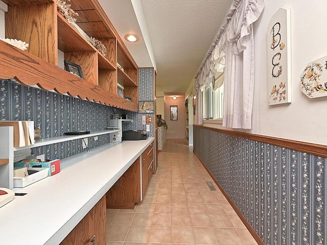 hallway with a textured ceiling and light tile patterned floors