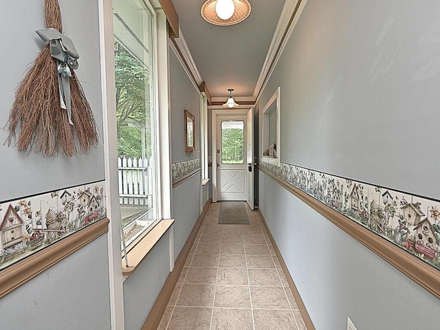 hallway with ornamental molding and light tile patterned flooring