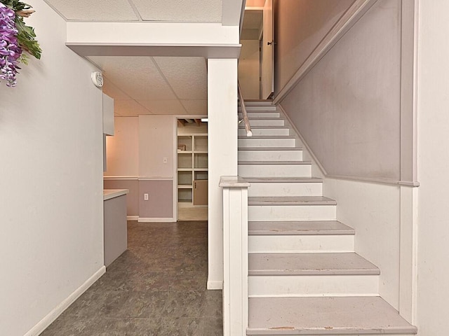 stairs with tile patterned floors and a drop ceiling