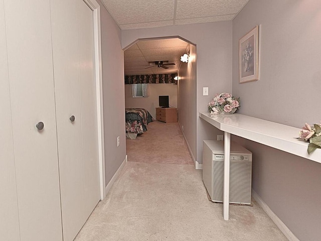 hall featuring light carpet and a paneled ceiling