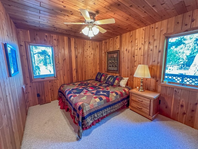 bedroom with wooden ceiling, light colored carpet, wooden walls, and ceiling fan