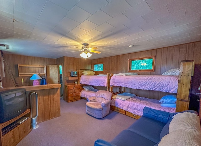 bedroom featuring carpet flooring, wooden walls, and ceiling fan