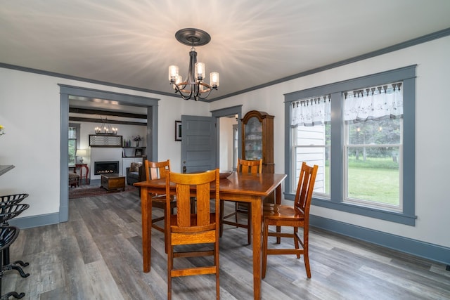 dining space featuring wood-type flooring, a chandelier, and crown molding