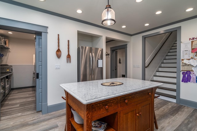 kitchen with ornamental molding, hardwood / wood-style flooring, pendant lighting, and stainless steel refrigerator with ice dispenser