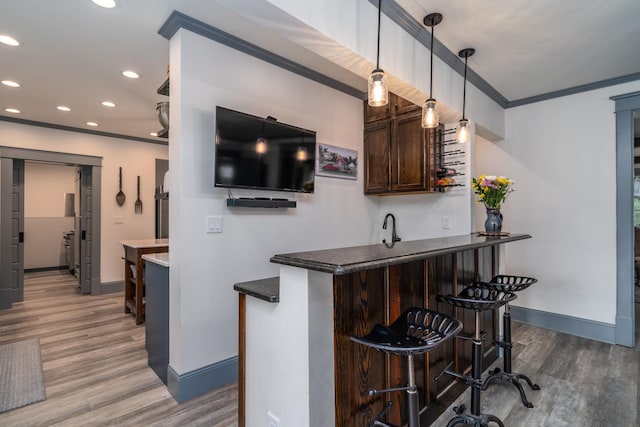 bar featuring hardwood / wood-style flooring, ornamental molding, dark brown cabinetry, and hanging light fixtures