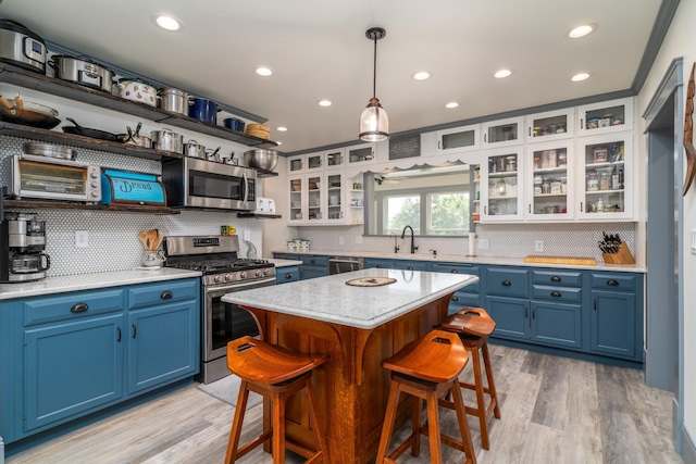 kitchen featuring white cabinetry, stainless steel appliances, a kitchen island, blue cabinets, and sink