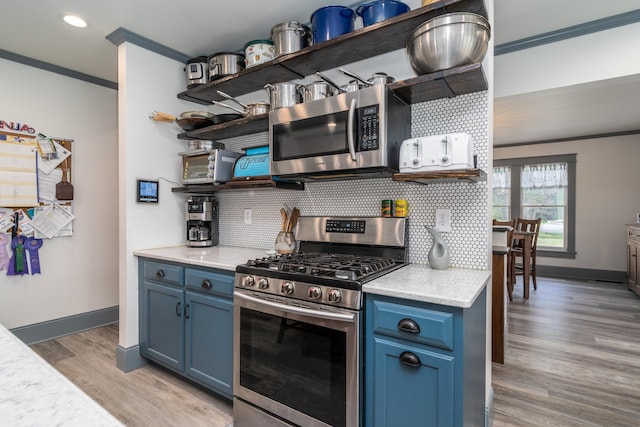 kitchen featuring blue cabinetry, light hardwood / wood-style floors, crown molding, stainless steel appliances, and tasteful backsplash