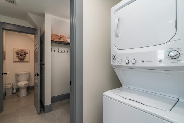 laundry area featuring light tile patterned floors and stacked washer and clothes dryer