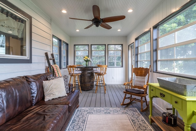 sunroom featuring ceiling fan, bar area, and a healthy amount of sunlight