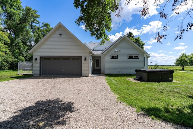 view of front of property with a garage, a hot tub, and a front yard