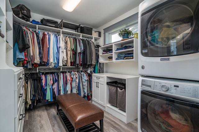 laundry room with hardwood / wood-style flooring and stacked washer / dryer