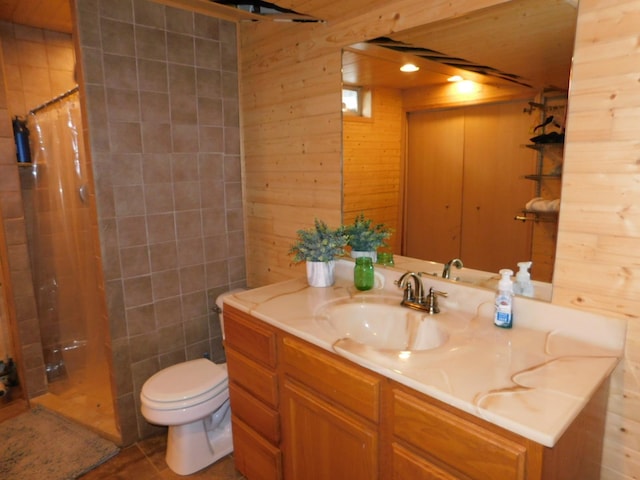 bathroom featuring a shower with curtain, vanity, wooden walls, tile patterned flooring, and toilet