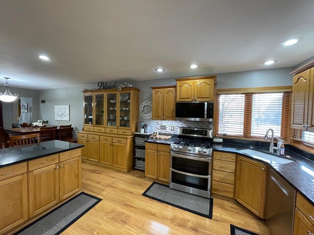675 10th St, Granite Falls, MN 56241 - kitchen with appliances with stainless steel finishes, dark countertops, light wood finished floors, brown cabinetry, and recessed lighting