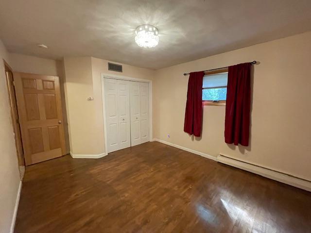 675 10th St, Granite Falls, MN 56241 - unfurnished bedroom with dark wood-style flooring, a closet, and a baseboard heating unit