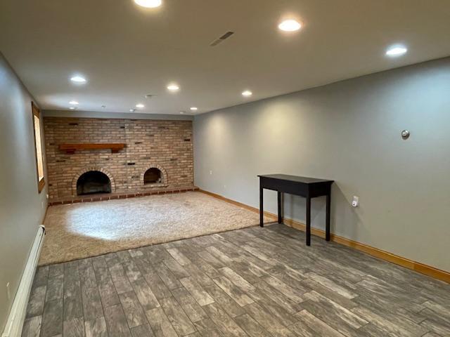 675 10th St, Granite Falls, MN 56241 - unfurnished living room with a brick fireplace, wood finished floors, recessed lighting, and baseboard heating