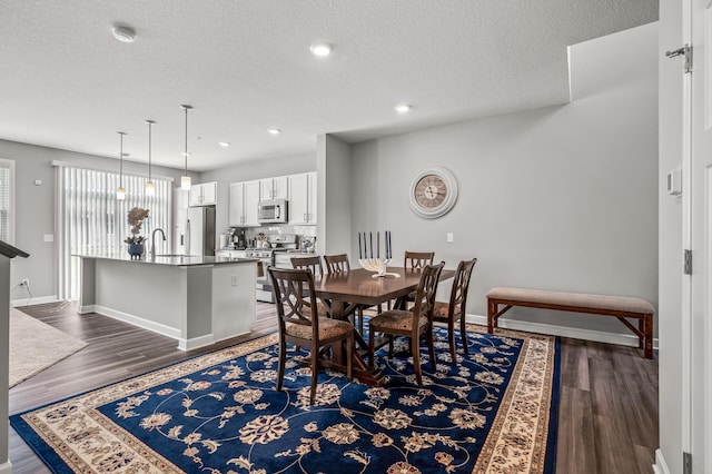 dining space featuring sink, a textured ceiling, and dark wood-type flooring