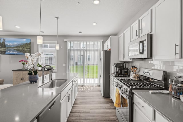 kitchen with white cabinetry, backsplash, light hardwood / wood-style floors, appliances with stainless steel finishes, and sink