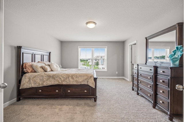 bedroom with multiple windows, a textured ceiling, and light colored carpet