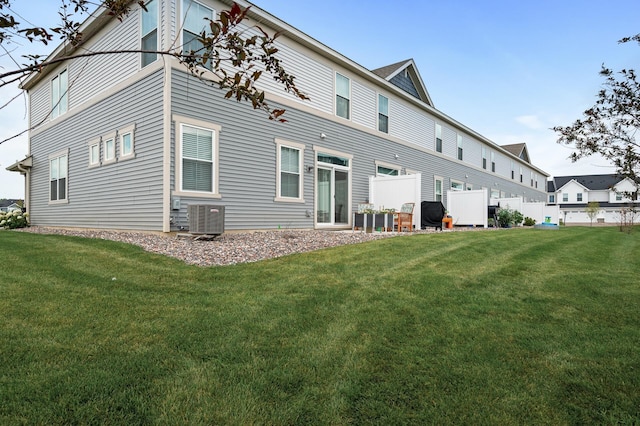 rear view of property featuring cooling unit and a lawn