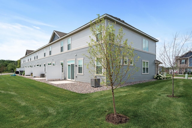 rear view of property with central AC and a yard