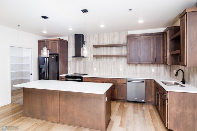 kitchen with sink, wall chimney exhaust hood, stainless steel appliances, light hardwood / wood-style floors, and decorative light fixtures